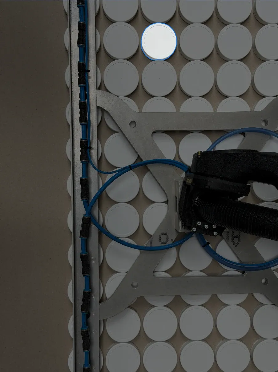 Tray of moulded lids on the take-out robot, one lid picked out by the inspection lighting