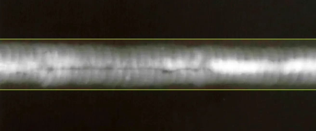 X-ray image of a weld on a metal part with a dark indication running along the root